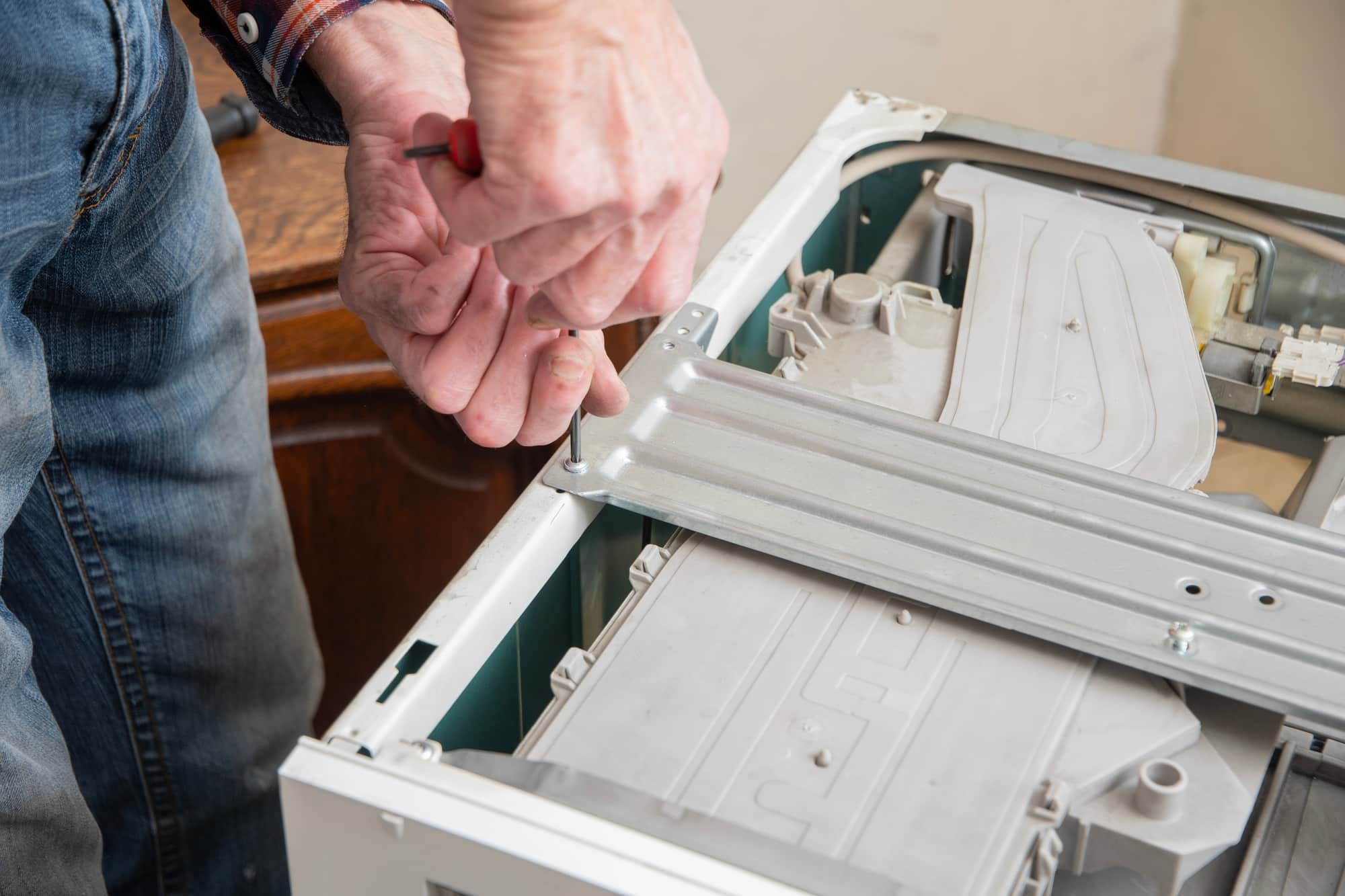 Middle aged man repairing broken washing machine with tools, household chores